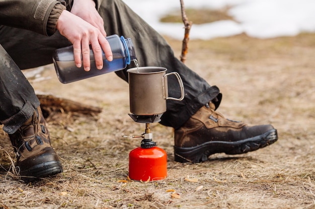 Male hunter preparing food with a portable gas burner in a winter forest