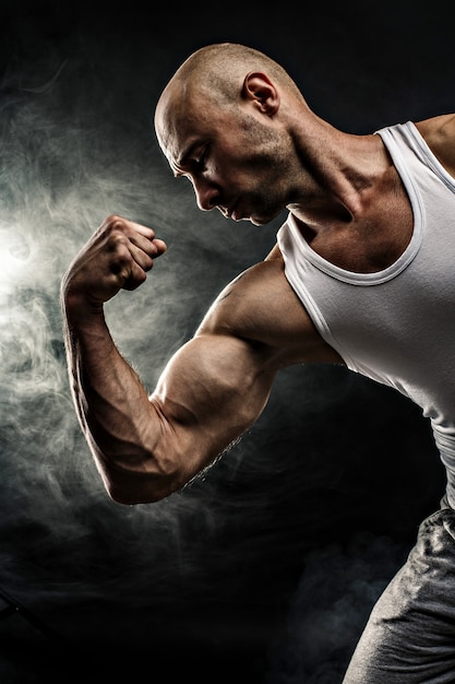Фото Кобель в белой майке с сильными мышцами на черном фоне