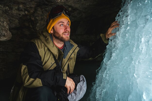 写真 凍った壁を見つめている氷の洞窟の冬装の男性