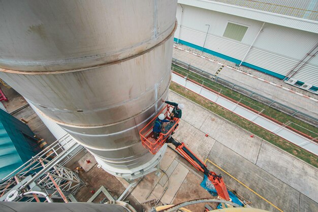 Male industry working at high in a boom liftinspection tank silo