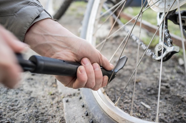 男性はポンプで自転車の車輪を膨らませます。閉じる