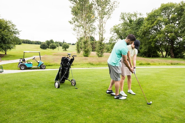 Male instructor assisting woman in learning golf