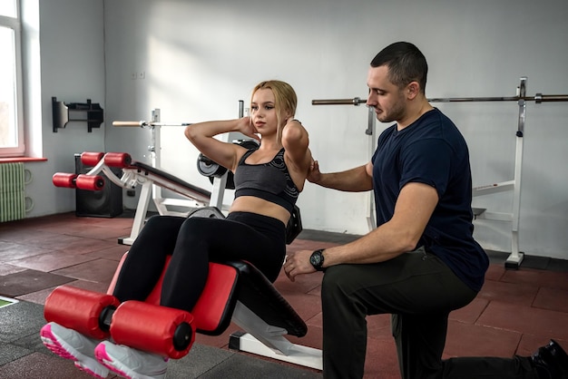 Male instructor exercising with his female client at gym woman working about the optimal training program