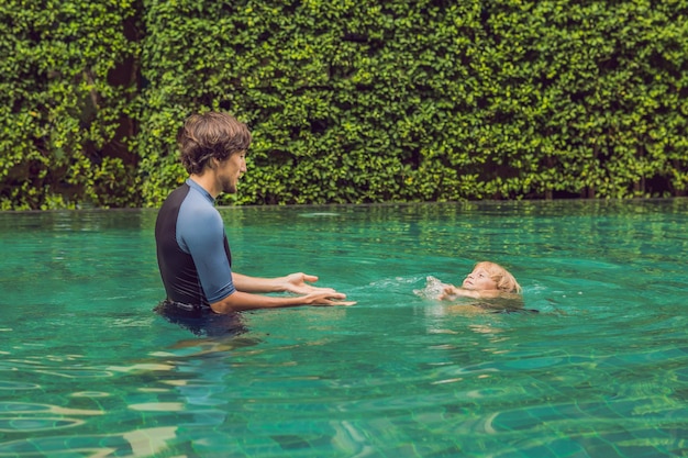 Male instructor swimming for children teaches a happy boy to swim in the pool