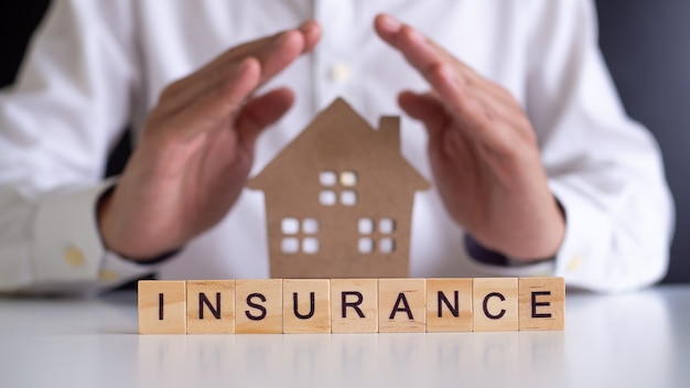 남자 보험 대리인이 집을 보호하기 위해 손을 사용하고 있습니다. 주택 보험 또는 주택 보험 개념