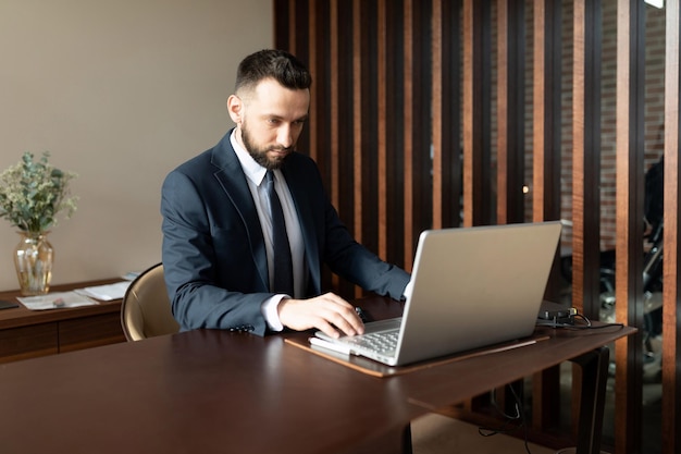 male insurance agent in a suit in the office working on a laptop