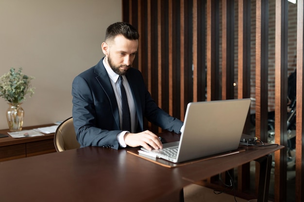 Male insurance agent in a suit in the office working on a laptop