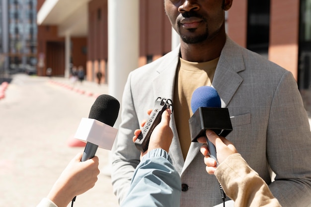 Male interviewed by journalists outdoors