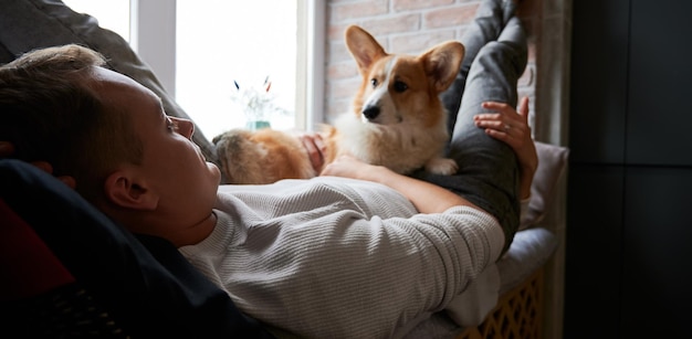 Male is resting with his pet on windowsill bed