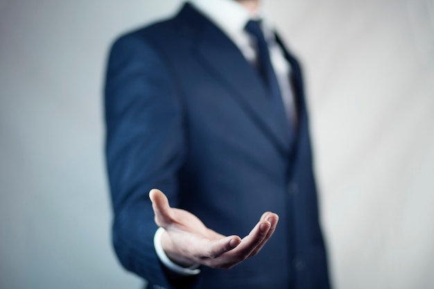 Male is standing and shows outstretched hand with open palm