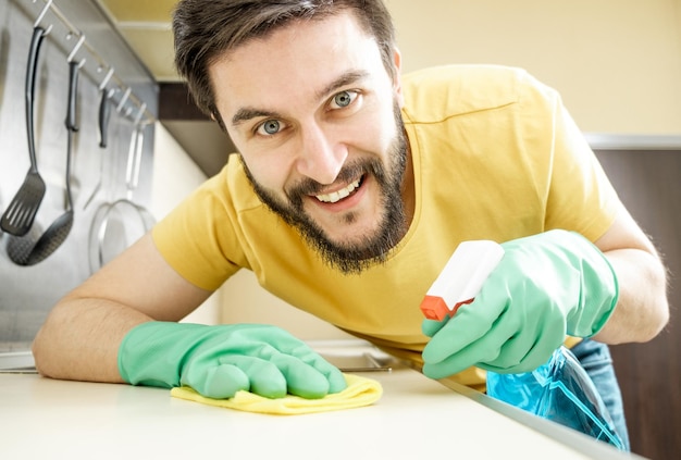 Male janitor cleaning kitchen with sponge