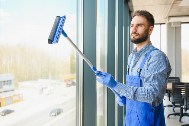 Photo male janitor cleaning window in office