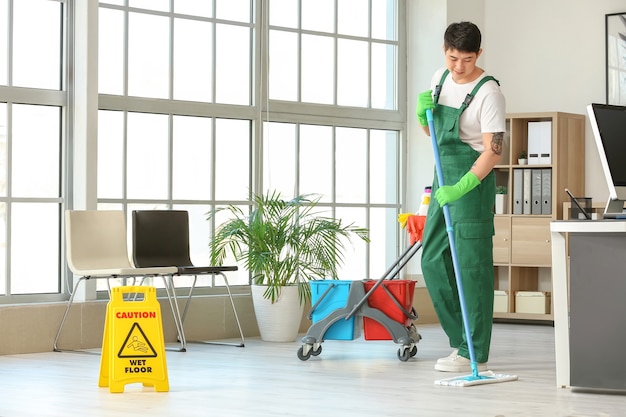 Male janitor mopping floor in office