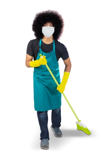 Male janitor wears mask while holding a broom