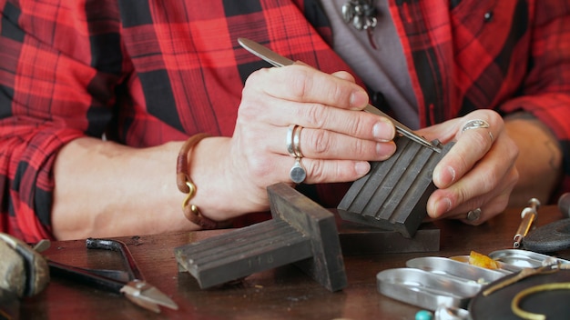 Male jeweler works at his workplace in a jewelry workshop. Favorite work.