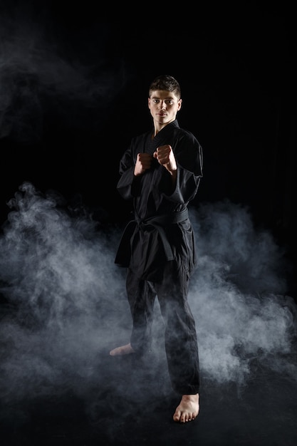 Фото Боец каратэ в черном кимоно, боевая позиция. человек на тренировке, боевых искусствах, боевых соревнованиях