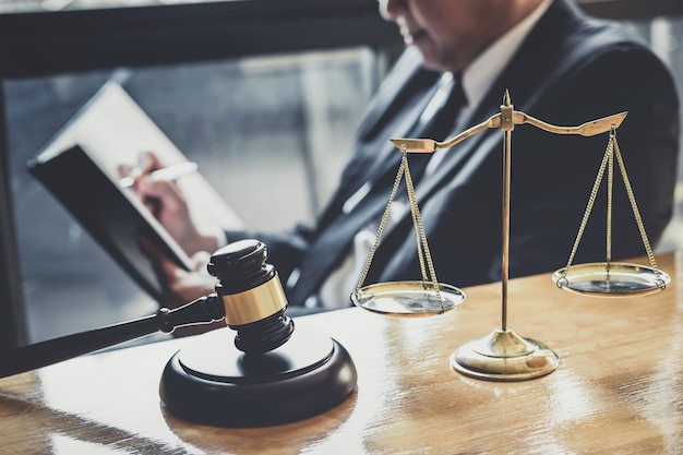 Male lawyer or judge working with contract papers, Law books and wooden gavel on table in courtroom