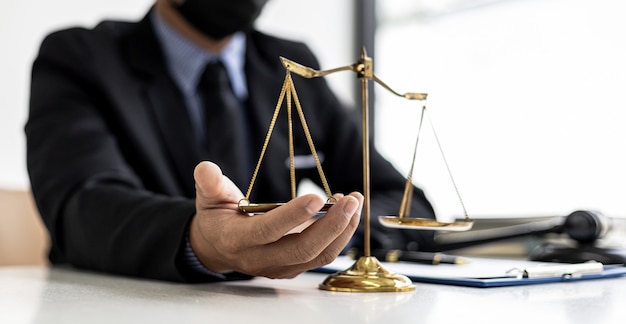 The male lawyer puts a second hand on the scales of justice on his desk, stating that the matter must be justified and not contrary to law and humanity. The concept of legal jurisprudence.