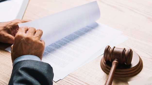 Мужской адвокат переворачивает документы в зале суда на деревянном столе