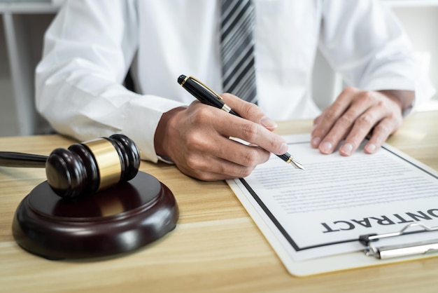 Male lawyer working with litigation contract paper documents of the estate lawsuit, Law books and wooden gavel on table office.