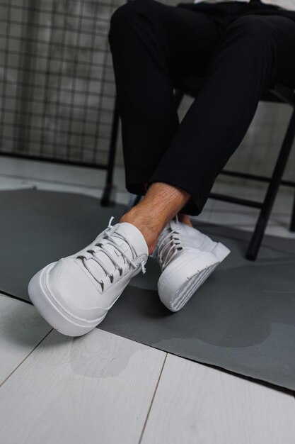 Male legs in black pants and white casual sneakers Men's fashionable shoes