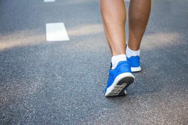 Male legs in running shoes outside on asphalt road