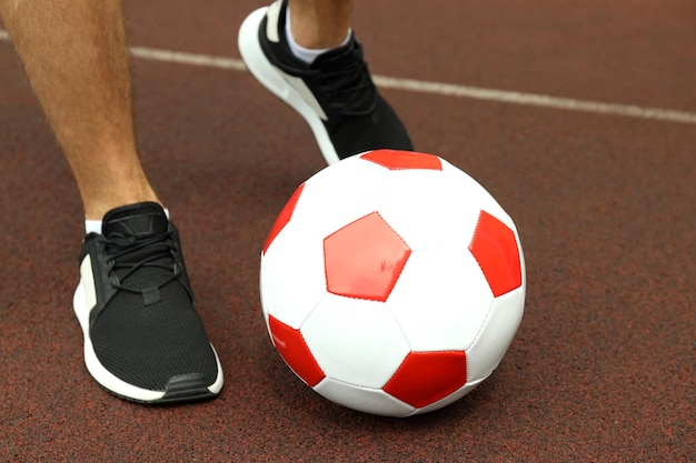 Male legs in sneakers and football ball