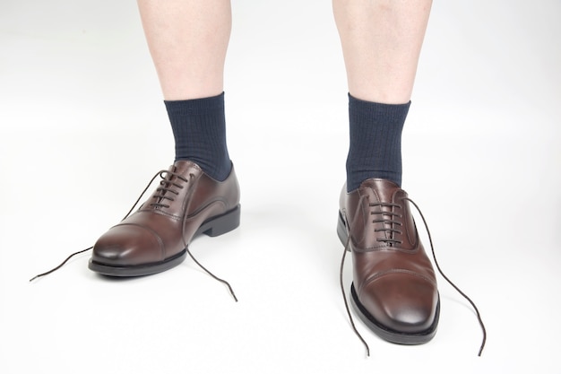 Male legs in socks and brown classic leather shoes on a white