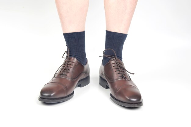 Male legs in socks and brown classic shoes on a white background