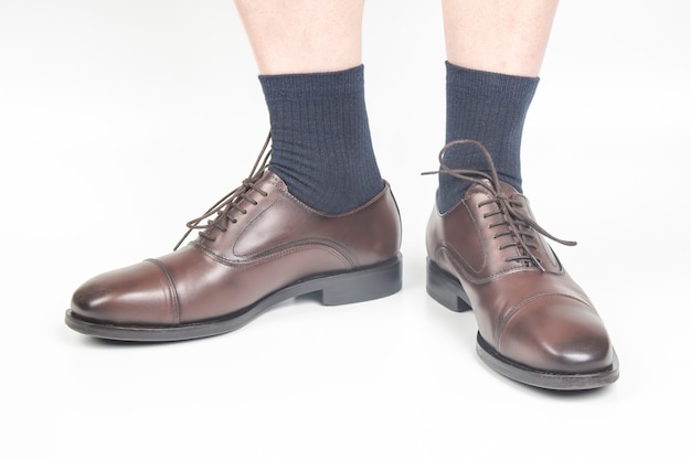 Male legs in socks and brown classic shoes on a white background