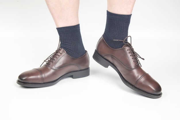 Male legs in socks and brown classic shoes on a white background