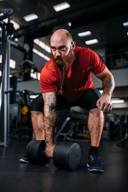 Male lifter doing exercise with dumbbells in gym