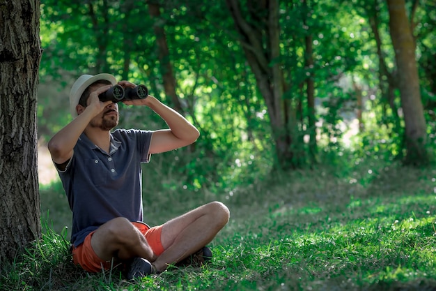 Male looking through binoculars in forest