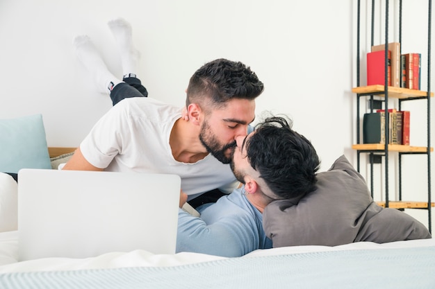 Male lovers lying on bed kissing each other