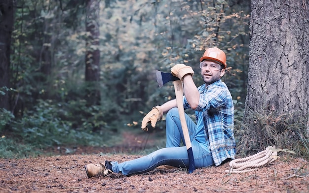 Male lumberjack in the forest. A professional woodcutter inspects trees for felling.