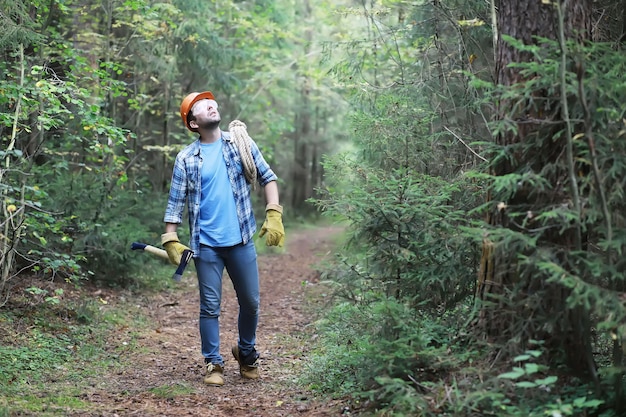 Male lumberjack in the forest. A professional woodcutter inspects trees for felling.