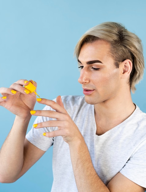 Photo male make-up look painting his nails in yellow