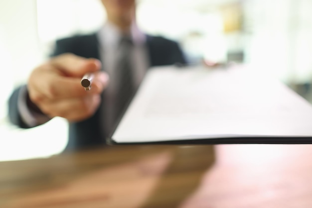 Male manager gives pen and clipboard with contract papers