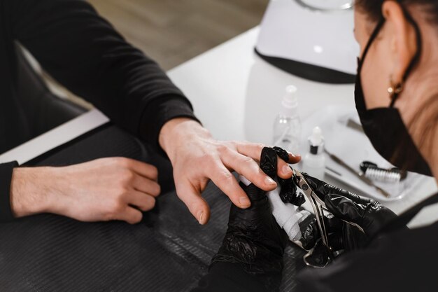 Male manicure close up view of the nail service master doing manicure for man