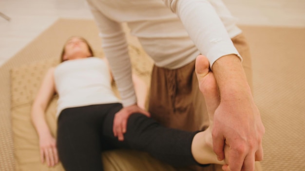 Male masseur holds the thai massage session  stretching of the legs and foots