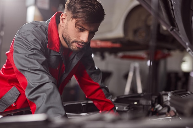 Male mechanic examining car engine