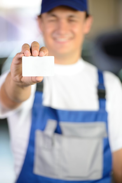 Photo male mechanic holding a business card in front of him.