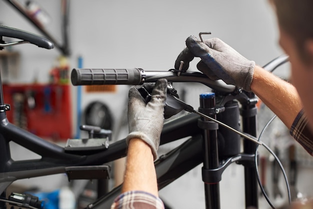 Male mechanic making service in bicycle repair shop using tools