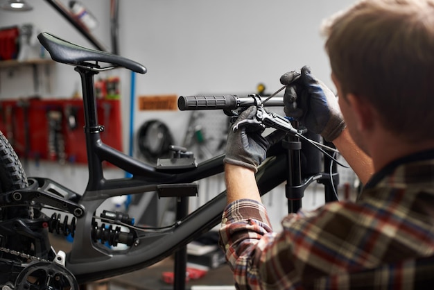 Male mechanic making service in bicycle repair shop using tools