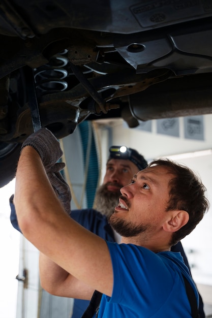 写真 自動車修理工場で車に取り組んでいる男性整備士