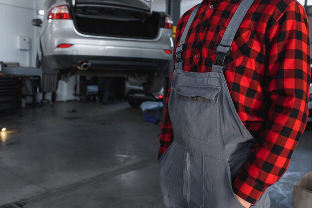 Male mechanic working at a repair shop and holding tools