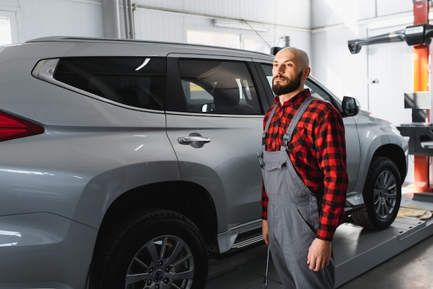 Male mechanic working at a repair shop and holding tools