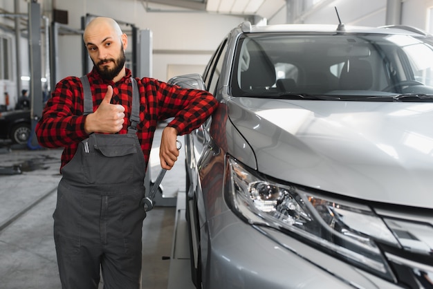 Male mechanic working at a repair shop and holding tools