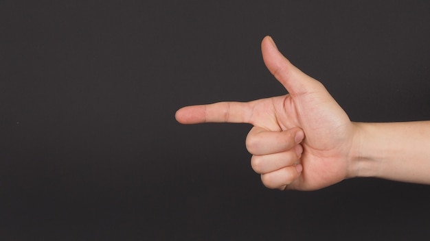 Male model is point the finger with right hand to do sign on black background.