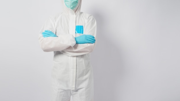 Male model isl wearing PPE suite and face mask.He is standing and fold one's arms over the chest on white background.